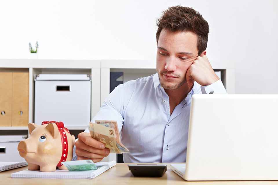 Foto: Mann mit Taschenrechner und Bargeld